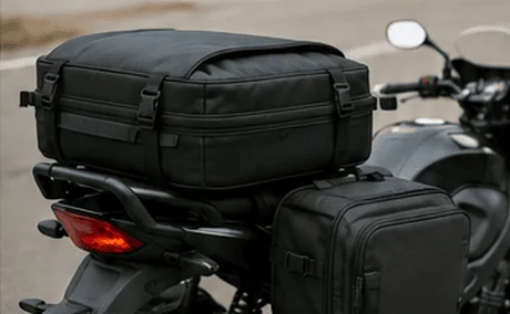 Sac installé à l’arrière d’une moto, avec une sacoche latérale et le feu arrière visible.