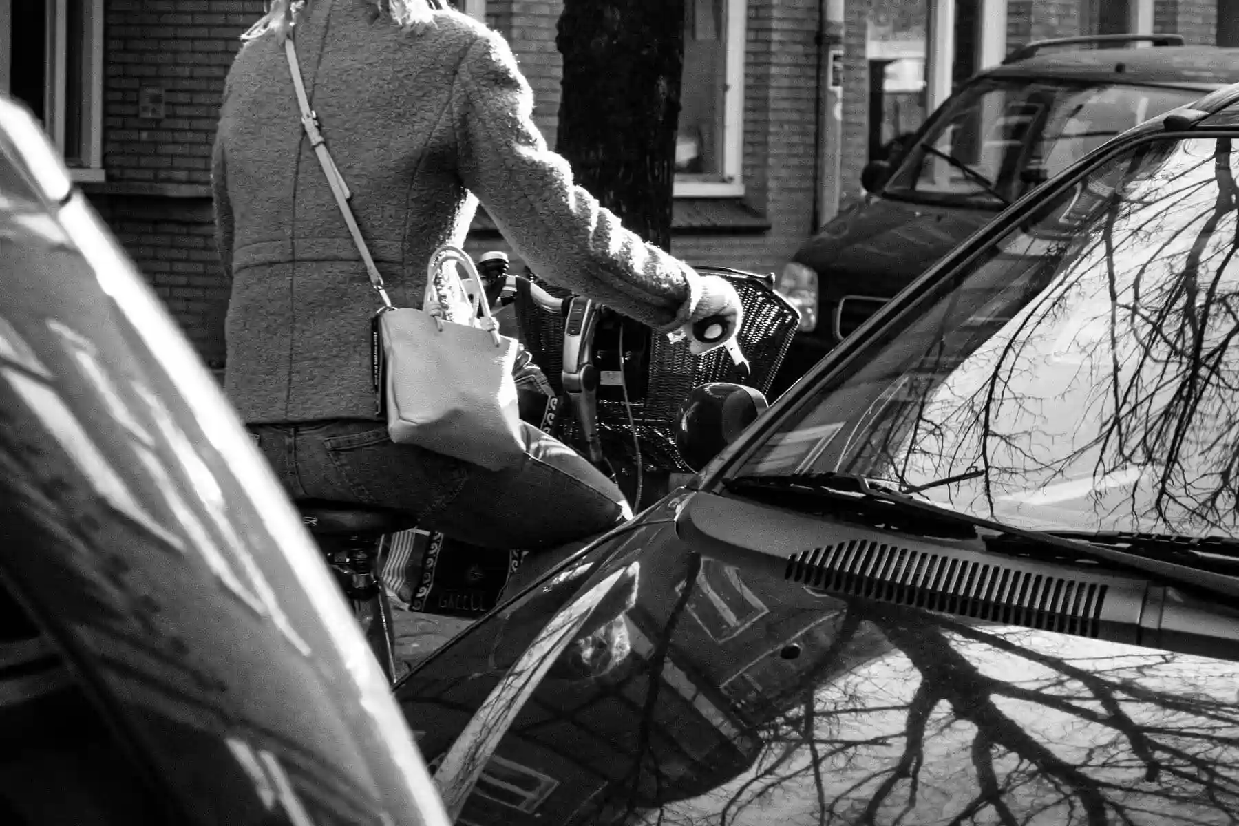 Une cycliste passe dans un espace étroit entre des voitures.