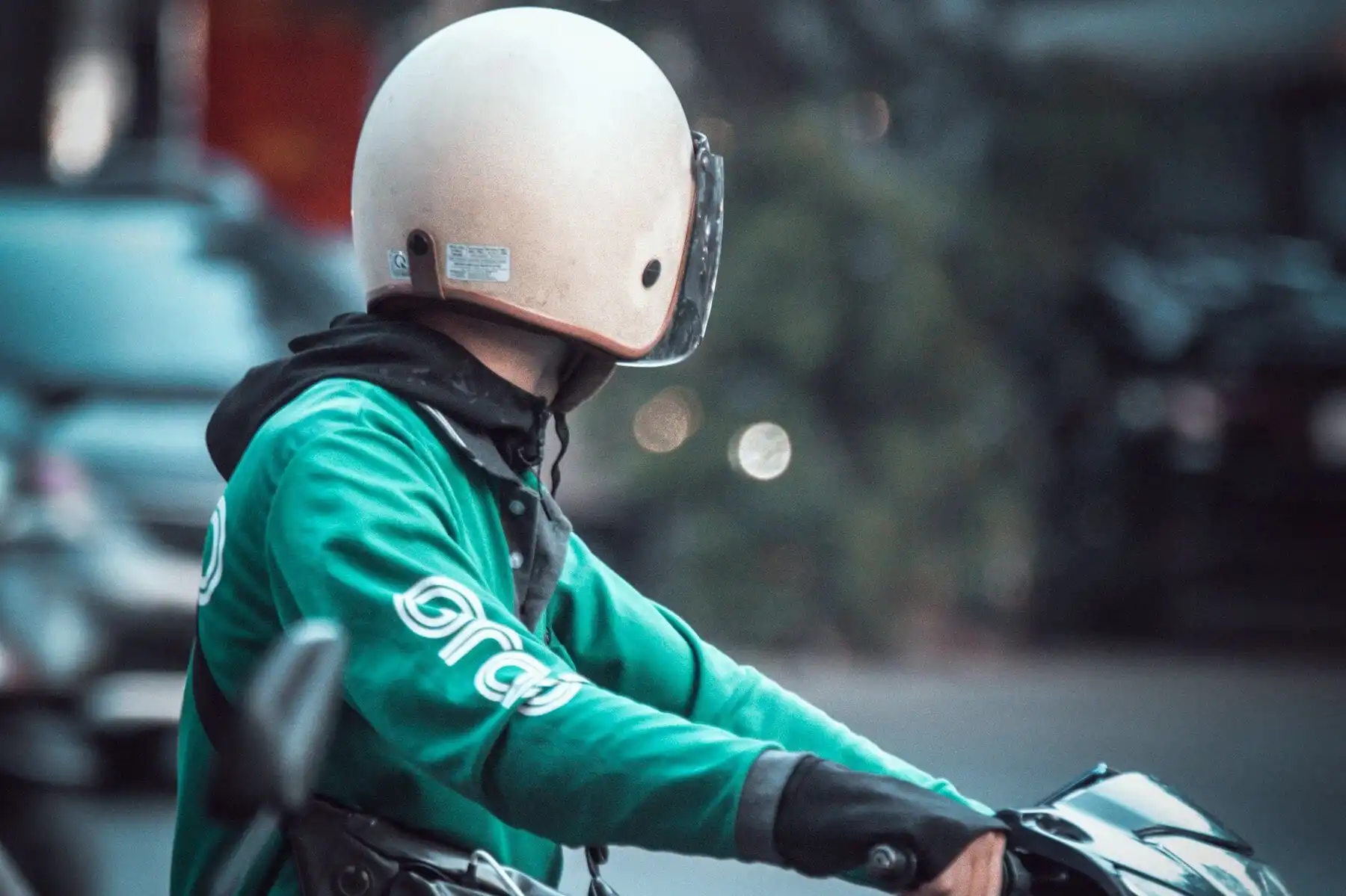 Conducteur de scooter portant un casque à visière, la tête tournée sur le côté.