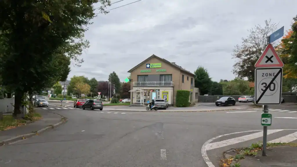Carrefour avec, à droite, un panneau triangulaire à croix noire au-dessus d’un panneau de fin de zone 30.