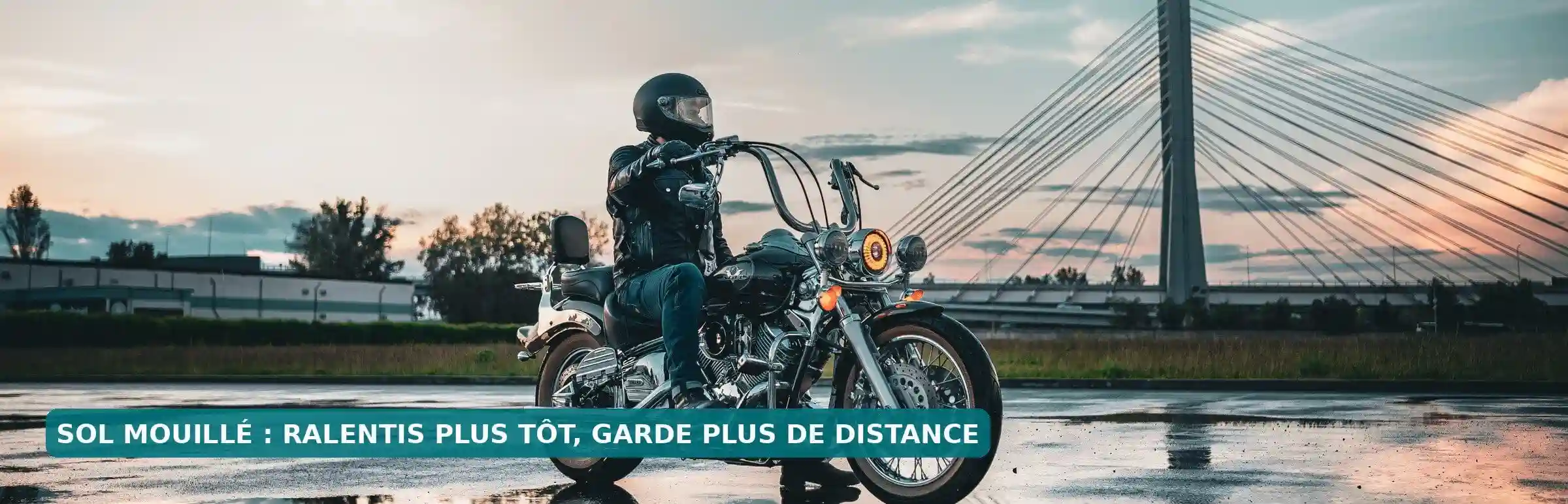 Motard sur une chaussée mouillée, avec des flaques et des reflets au sol.