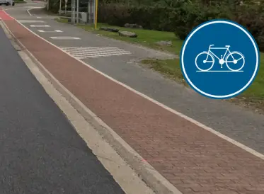 Piste cyclable rouge séparée de la chaussée par une bordure, avec un panneau rond bleu au vélo blanc ajouté en surimpression.