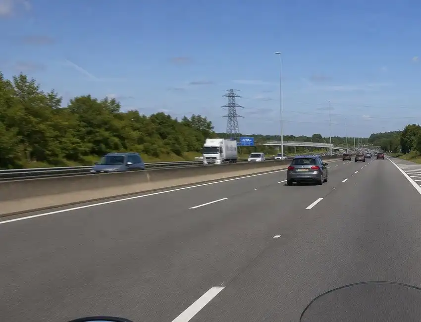 Autoroute à plusieurs bandes, avec une séparation centrale, des véhicules espacés et une vue dégagée au loin.
