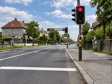 Feu rouge à droite et ligne blanche transversale située avant le poteau du feu.