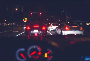 Des voitures immobilisées en file devant des feux rouges, vues depuis l’habitacle.