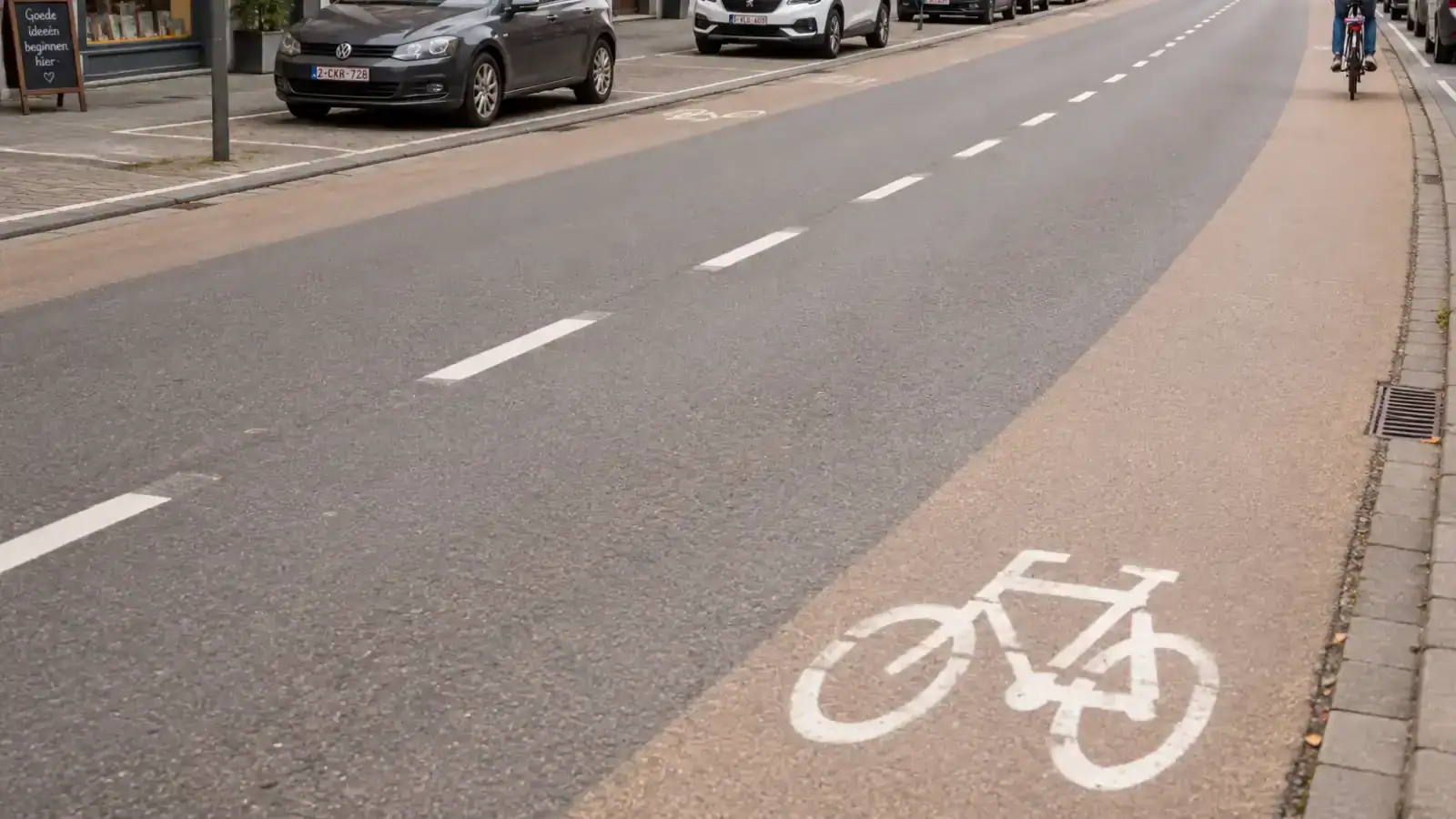 Bandes latérales colorées portant des pictogrammes de vélo, sans ligne blanche les séparant du reste de la chaussée.