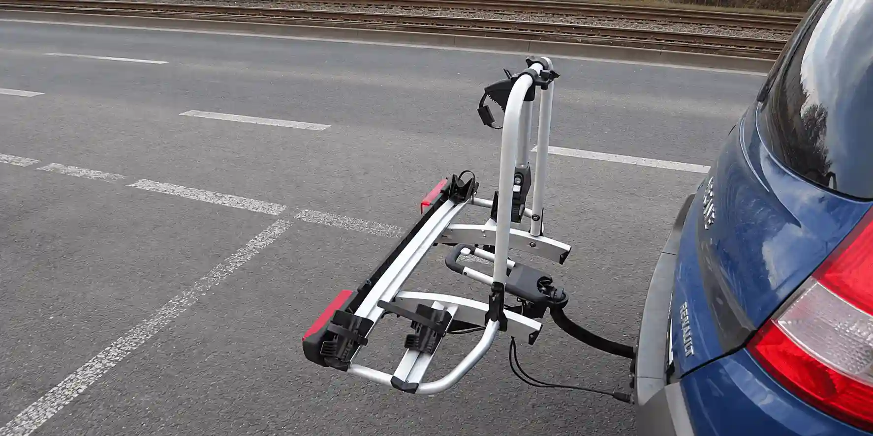 Porte-vélos vide à l’arrière d’une voiture, avec supports de roues, bras de maintien et blocs de feux.