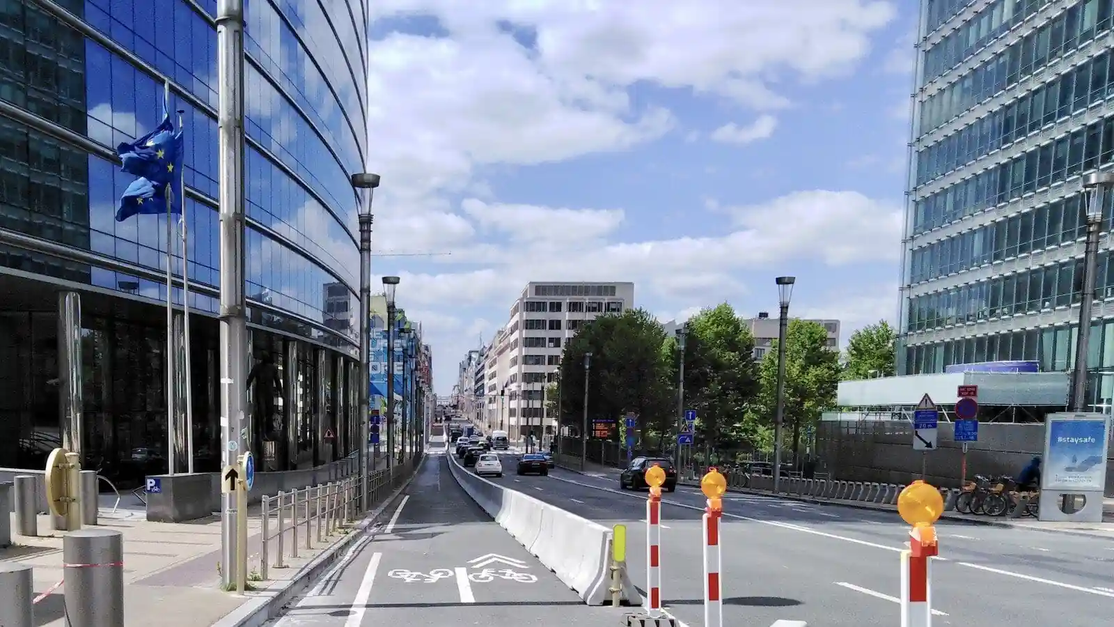 Piste cyclable longeant la chaussée, séparée de la circulation automobile par des barrières en béton.