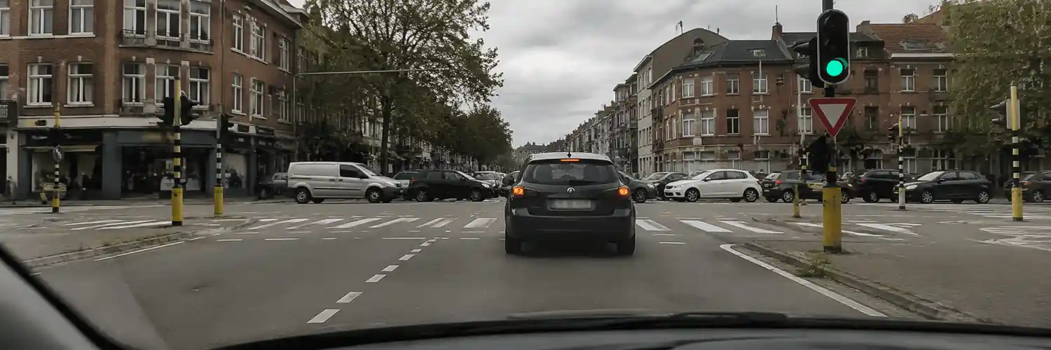 Feu vert à droite, voiture juste devant et plusieurs véhicules occupant le carrefour.