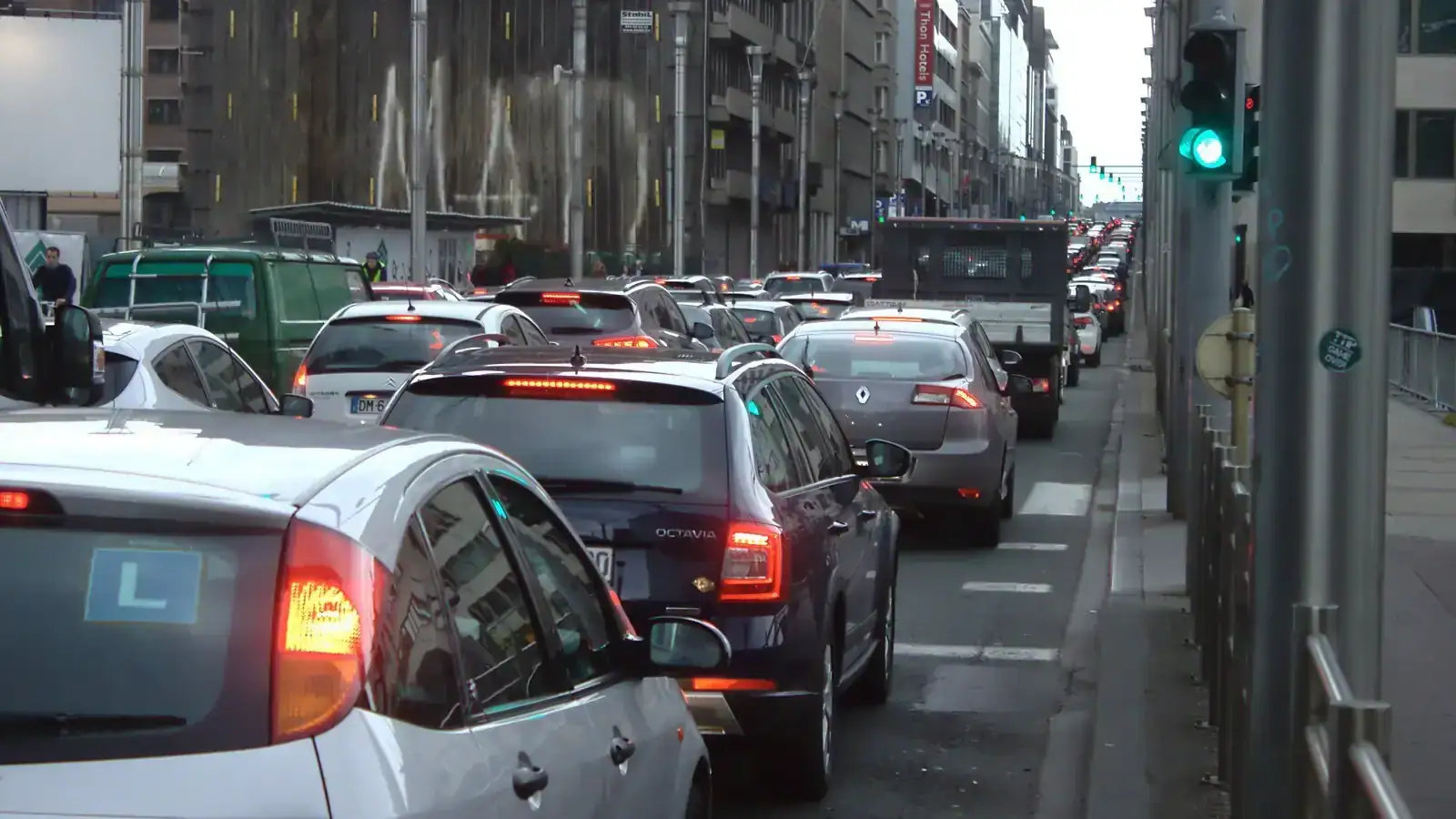 Des files de véhicules serrés s’étendent au loin dans une rue ; des feux-stop sont allumés au premier plan et sur plusieurs voitures plus loin.