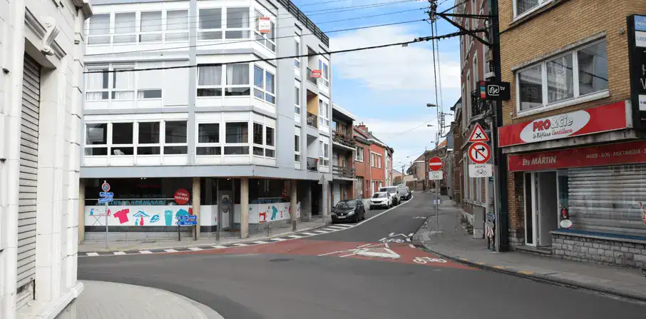 Rue sans ligne axiale, avec un signal de sens interdit et un signal interdisant de tourner à droite, chacun accompagné d’une exception pour les cyclistes.