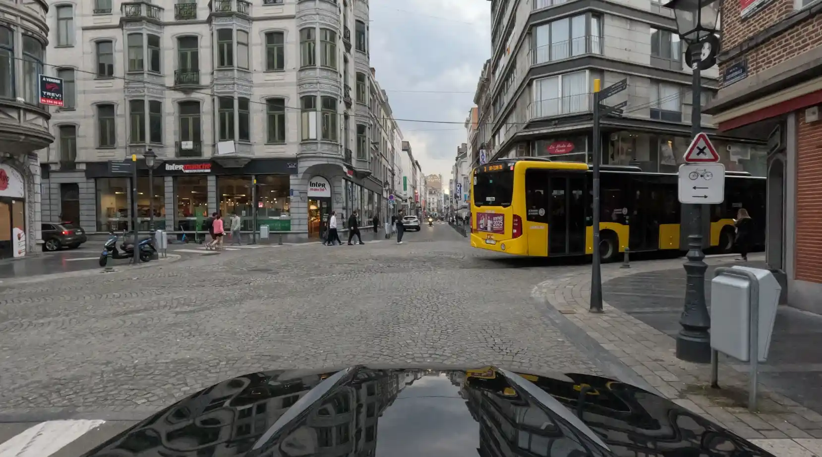 Un bus occupe une partie du carrefour tandis que des piétons traversent la rue en face.