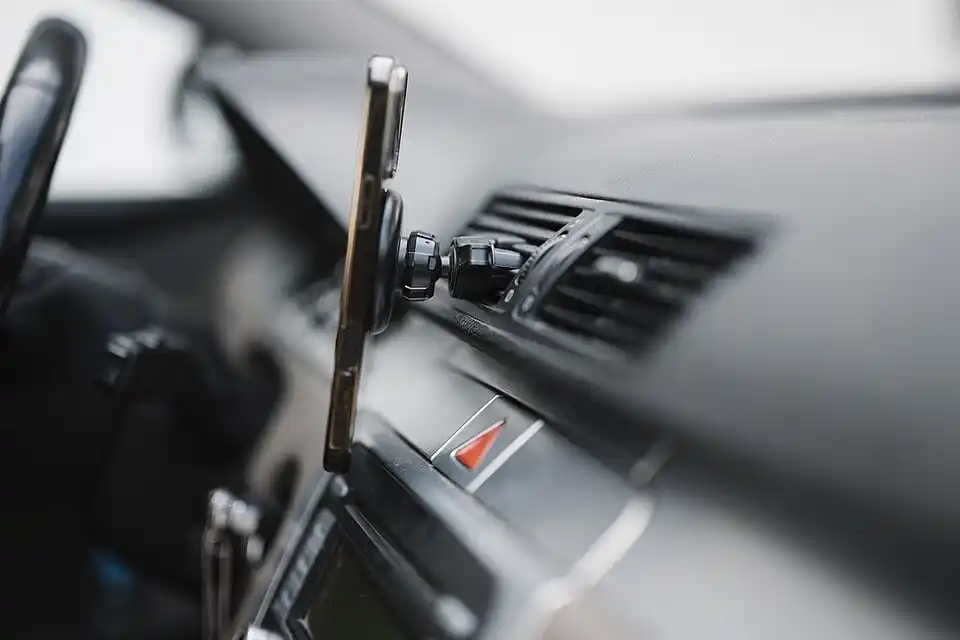 Téléphone fixé à une grille d’aération du tableau de bord par un support.