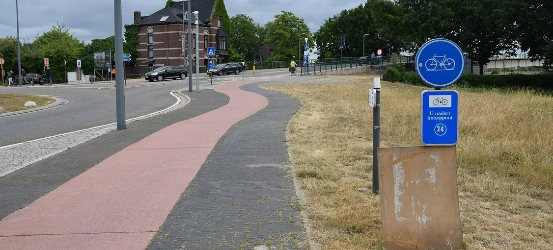 Piste cyclable séparée de la chaussée à Maaseik, avec un revêtement coloré et un signal D7.