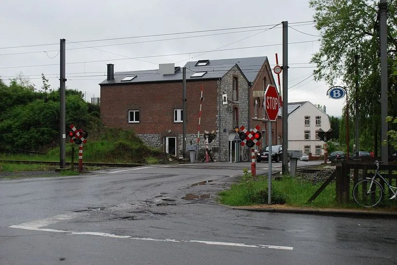 À Barvaux, panneau STOP avant un passage à niveau avec barrières levées et feu rouge allumé.