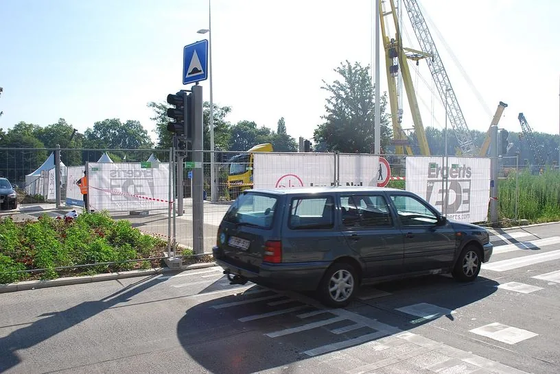 Voiture franchissant un aménagement surélevé marqué de bandes blanches ; à gauche, panneau bleu avec un triangle blanc et une bosse noire.