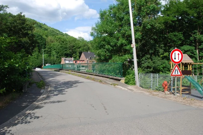 À l’entrée d’un pont étroit près de Tilff, panneau rond bordé de rouge avec une flèche rouge vers le haut et une flèche noire vers le bas, au-dessus d’un signal de rétrécissement.
